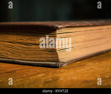 old photo album lies on a wooden table in the room. Closed book. Retro. Closeup. Stock Photo