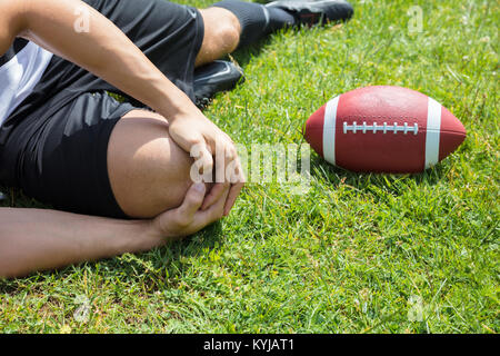 Close-up Of Male Rugby Player Suffering From Knee Injury Lying On Field Stock Photo