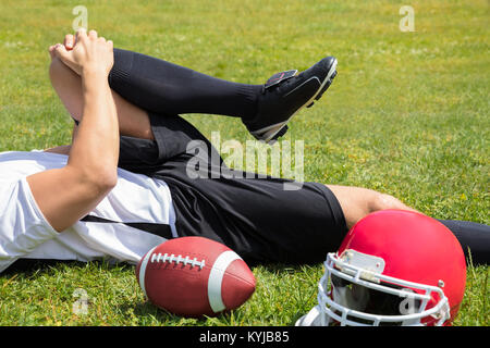 Close-up Of Injured American Football Player Lying On Field With Rugby And Helmet Stock Photo