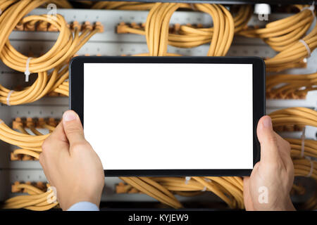 Male Technician's Hand Holding Blank Digital Tablet In Front Of Server Stock Photo