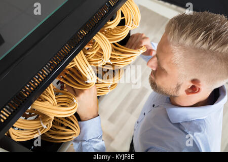 Close-up Of Male Technician Checking Server's Wires In Data Center Stock Photo