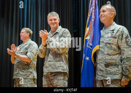 Chief Master Sgt. Ray Dawson (right), command chief master sergeant for the Kentucky Air National Guard’s 123rd Airlift Wing, holds the wing guidon during an award ceremony at Louisville Male High School in Louisville, Ky., July 13, 2014, as Maj. Gen. Edward W. Tonini (left), Kentucky’s adjutant general, and Col. Barry Gorter, wing commander, applaud. The ceremony was held to present the wing with its 16th Air Force Outstanding Unit Award. (U.S. Air National Guard photo by Senior Airman Joshua Horton) Stock Photo