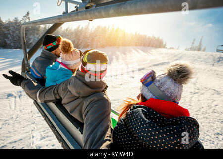 skiers and snowboarders on ski lift in the mountain at winter vacations back view Stock Photo