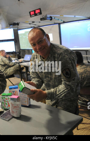 Chief Warrant Officer 2 Scott Goode, information technology systems officer, grabs a box of Girl Scout cookies April 27, at Camp Atterbury, Indiana, during the Vibrant Response 2015 exercise. Girl Scout Troop #1199, a Taylorsville, Kentucky-based troop, donated boxes of cookies to the Kentucky National Guard's Headquarters and Headquarters Company, 63rd Theater Aviation Brigade, which passed out the cookies during annual training. The cookies were used as a service project to earn the Troop to Troops badge for the Girl Scouts. (U.S. Army National Guard photo by Sgt. 1st Class Gina Vaile-Nelson Stock Photo