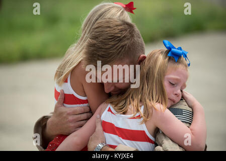 Capt. Ross Farling, a C-130 pilot in the 123rd Airlift Wing, hugs his daughters during an emotional homecoming ceremony at the Kentucky Air National Guard Base in Louisville, Ky., July 4, 2015. Farling was among 39 Kentucky Air Guardsmen who were returning from a deployment to the Persian Gulf region, where they've been supporting Operation Freedom's Sentinel since February. Stock Photo