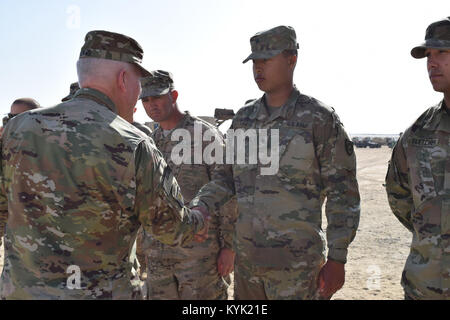 Spc. Alec Fugate with the 207th Horizontal Constuction company receives a coin from Brig. Gen. Benjamin Adams III, Kentucky's Director of the Joint Staff, Mar. 4 during a visit to Camp Arifjan, Kuwait. Stock Photo
