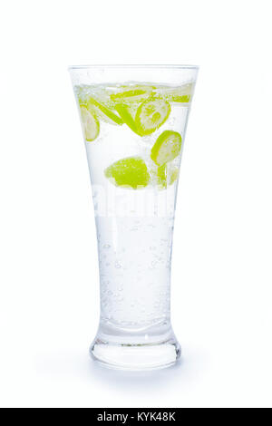Small green citrus fruit slices into drinking glass full of water with splash and bubbles. Isolated on white, clipping path included Stock Photo