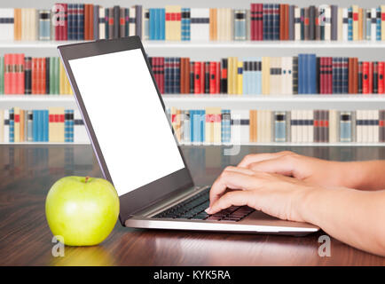 Close-up Of Woman Using Laptop With Green Apple On Table In The Library Stock Photo