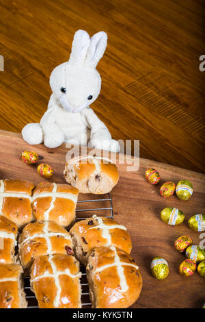 Fresh baked hot cross buns with plush toy rabbit and Easter Eggs Stock Photo