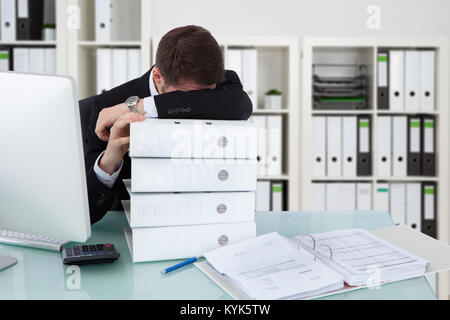 Businessman Sleeping On Stack Of Folders In Office Stock Photo