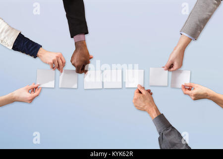 Closeup of resume on blue background - Businesspeople Arranging White Paper On Blue Background Kyk62r