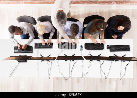 Elevated View Of Male Teacher Assisting Students In Computer Room Stock Photo
