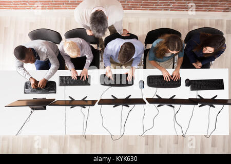 Elevated View Of Male Teacher Assisting Students In Computer Room Stock Photo