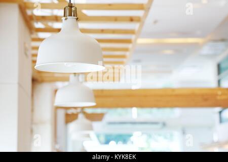 Close up of beautiful white simply modern ceiling lamps in restaurant with blurry background copy space.