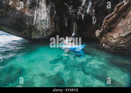 kayaker paddling in crystal clear water near the cave on Railay beach in Krabi, tourist travel on kayak in Thailand, blurred motion Stock Photo