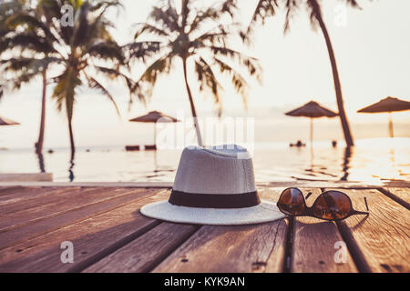 travel and tourism concept, sunglasses and hat near tropical swimming pool, beach holidays Stock Photo