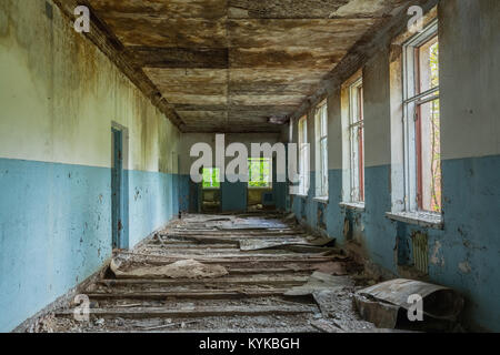 The Ruined Long Corridor Of Abandoned School After Chernobyl Disaster In Evacuation Zone. Consequences Of The Nuclear Pollution Twenty Years Later. Stock Photo