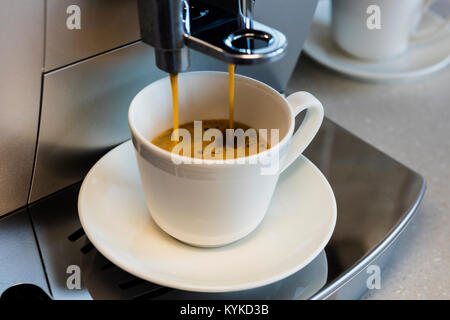 Coffee machine preparing espresso coffee into a small ceramic cup. Stock Photo