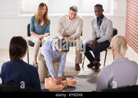 Young Male Instructor Showing CPR Training On Dummy To His Student Stock Photo