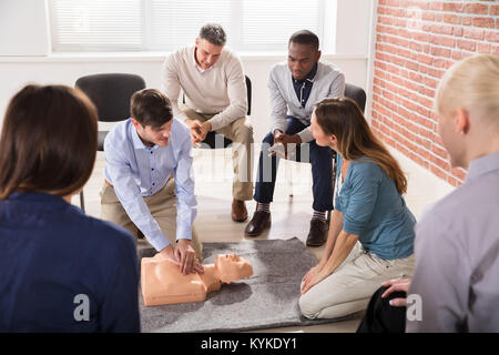 Young Male Instructor Showing CPR Training On Dummy To His Student Stock Photo