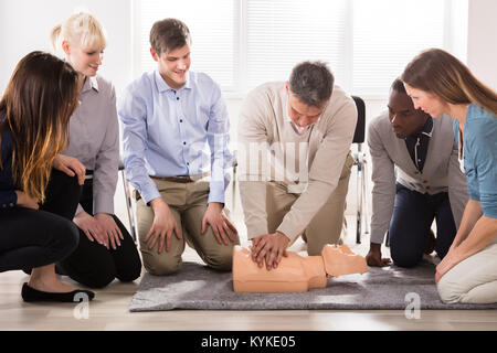 The Students Are Looking At The Instructor Performing Resuscitation Technique On Dummy Stock Photo