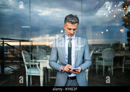 Businessman with smartphone in an outdoor hotel cafe. Stock Photo