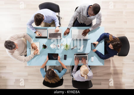 Elevated View Of Diverse Businesspeople Working On Desk Using Laptop And Digital Tablet Stock Photo