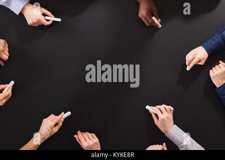 Overhead View Of Hands Drawing With Chalk On Blackboard Stock Photo