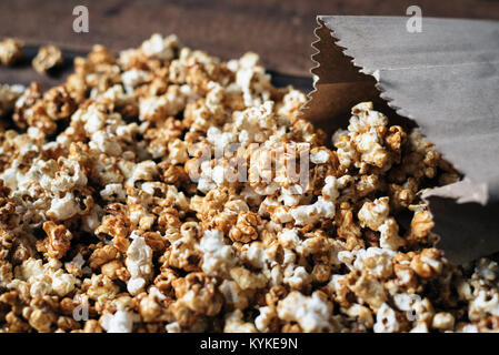 fresh caramel popcorn in a paper bag on wooden table Stock Photo