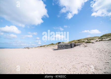 Danish beach with ruins of german bunkers from the 2nd word war in the summer with white clouds in the blue sky Stock Photo