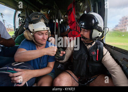 170924-N-VK310-0090 DOMINICA (Sept. 24, 2017) Naval Aircrewman (Helicopter) 2nd Class Andy Blessing 'fist bumps' an evacuee on an MH-60S Sea Hawk helicopter from Helicopter Sea Combat Squadron 22 (HSC-22), attached to the amphibious assault ship USS Wasp (LHD 1), during humanitarian aid operations on the embattled island of Dominica following the landfall of Hurricane Maria. The Department of Defense is supporting United States Agency for International Development (USAID), the lead federal agency, in helping those affected by Hurricane Maria to minimize suffering and is one component of the ov Stock Photo