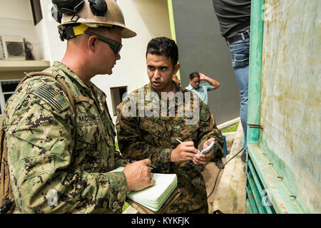 HUMACAO, Puerto Rico (Sept. 27, 2017) Construction Electrician 2nd Class John McConnell, left, assigned to Amphibious Construction Battalion (ACB) 2, annotates Spanish-English translations concerning a faulty generator to Hospitalman Apprentice Judd A. Ostolaza, a local resident and reservist assigned to Det. 1, Headquarters and Services Company, 4th Marine Logistics Group, volunteering his translating services with the 26th Marine Expeditionary Unit (26th MEU) as part of Hurricane Maria relief efforts at Ryder Hospital in Humacao, Puerto Rico. The Department of Defense is supporting the Feder Stock Photo