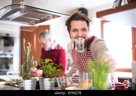 Hipster son with his senior father cooking in the kitchen. Stock Photo