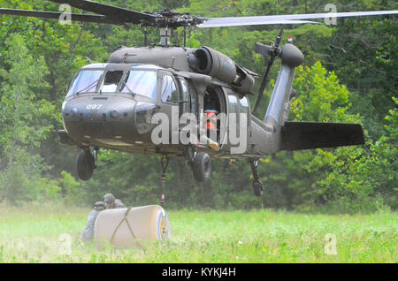 Water purification specialists with Alpha Company, 1204th Aviation Support Battalion, Kentucky National Guard, Burlington, Ky., connect a water blivet to a UH-60 Black Hawk while conducting sling load operations during the U.S. Army North (Fifth Army) led Vibrant Response 13-2 training exercise Aug. 2, 2013, at Camp Atterbury, Ind.  The water blivet will be used to supply water to soldiers at Forward Operating Base Night Hawk for hydration, cleaning and cooking purposes. Stock Photo