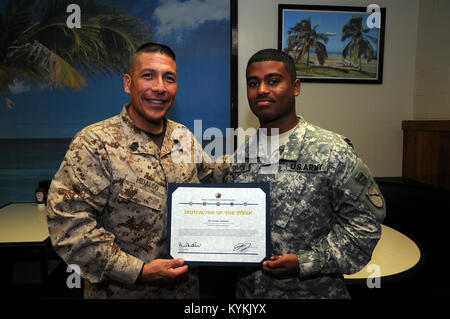 U.S. Marine Corps. Sgt. Maj. Juan Hidalgo, Jr., Senior Enlisted Leader at U.S. Naval Station Guantanamo Bay, Cuba, presents Kentucky Army National Guard Spc. Lerone Simmons, Public Affairs Specialist with the 133rd Mobile Public Affairs Detachment, with the Motivator of the Week Award Sept. 20, 2013 at U.S. Naval Station Guantanamo Bay, Cuba. The award was presented for outstanding morale and Esprit De Corp. Stock Photo