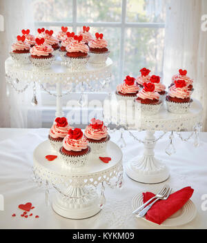 Cupcakes. Red velvet cupcakes decorated with red roses and hearts on 3 tier cakestand. Stock Photo