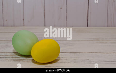Two Easter eggs, one yellow and the other one green on a wooden table Stock Photo