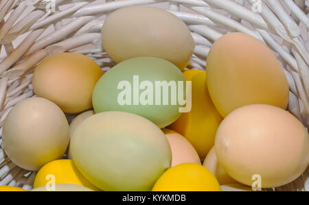 Different colored Easter eggs shown in a white wicker basket Stock Photo
