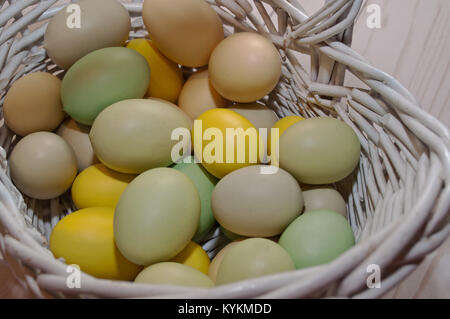 Different colored Easter eggs shown in a white wicker basket Stock Photo