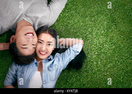 Top view of asian couple in love lying on a green grass at outdoor Stock Photo