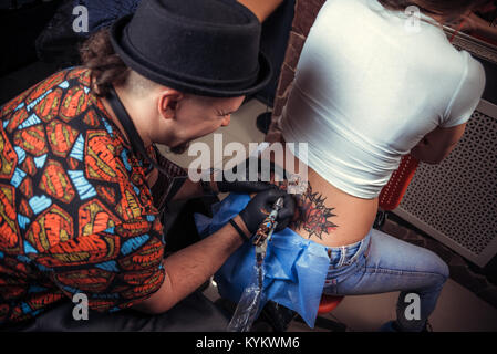 Professional tattooist makes a tattoo on the skin in his salon Stock Photo