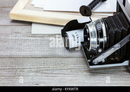 retro camera, film roll, photo frame and old pictures on grey wooden background Stock Photo