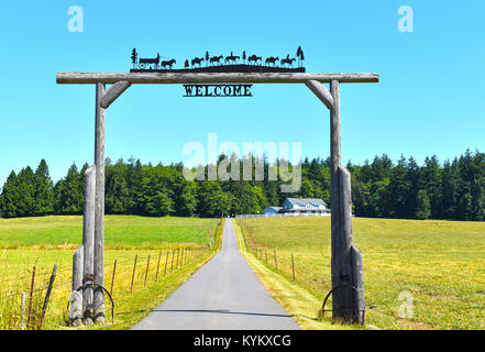 Beautiful ranch in the Pacific Northwest countryside of Ferndale, Washington, USA.  The wooden entrance has an old historical wagon pulled by horses a Stock Photo