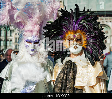 VENICE, ITALY - FEBRUARY 18, 2017: Two unidentified participants wear traditional vintage costumes and masks with feathers during famous Carnival. Stock Photo