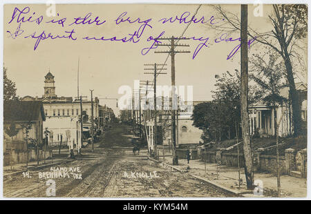 A historical photograph showing a street scene on Alamo Avenue in Brenham, Texas, with dwellings, stores, and telegraph lines visible. The image captures the small-town atmosphere of Texas in the early 20th century. Stock Photo