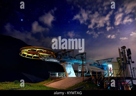 Cable car station with Lifeguard in red jacket in the door of building at the mountain ski resort with starry night sky Stock Photo