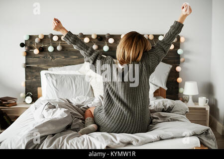 Rear view of woman stretching in her bed Stock Photo