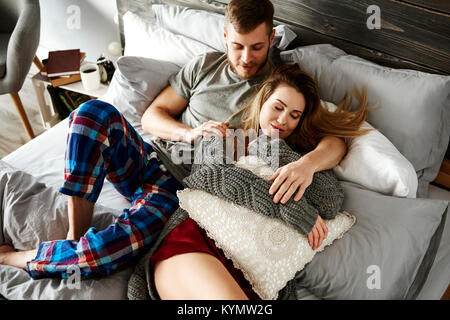 Embraced couple relaxing in bed Stock Photo