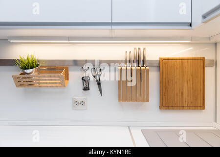 kitchenware hanging on the rail in the white glossy kitchen Stock Photo