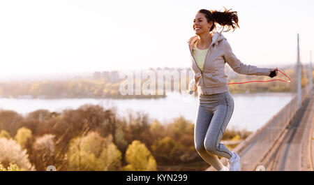 Active woman jumping with skipping rope outdoors Stock Photo